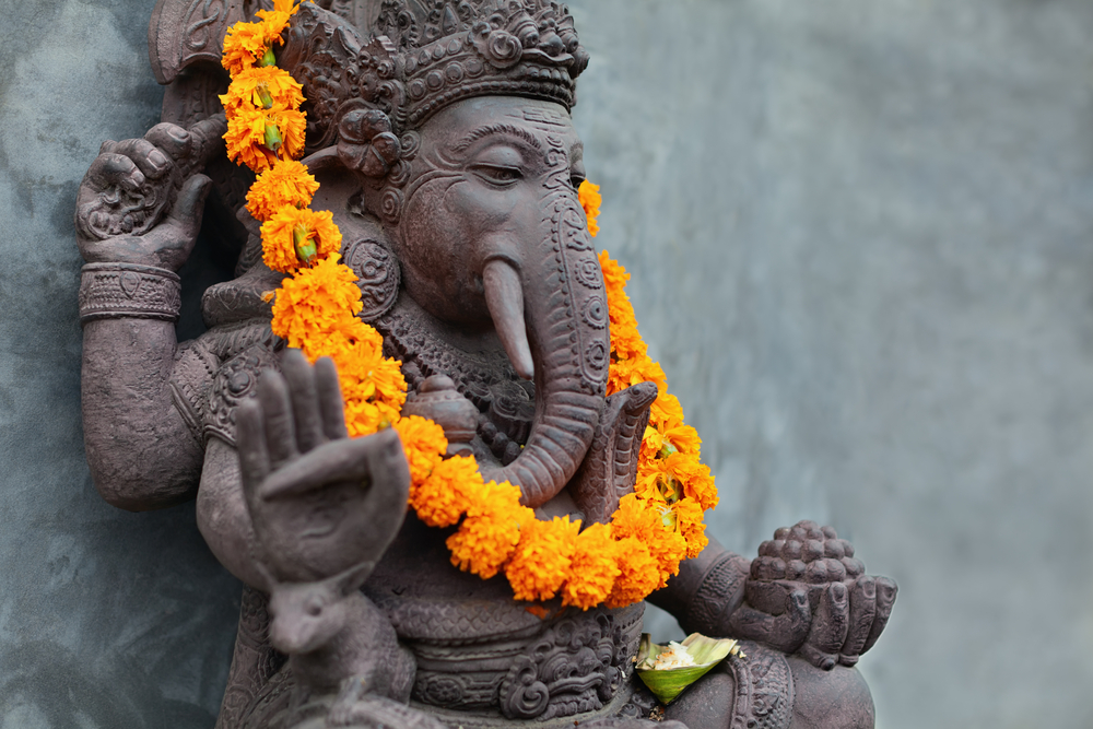 statue of Ganesh, wearing a wreath of orange flowers