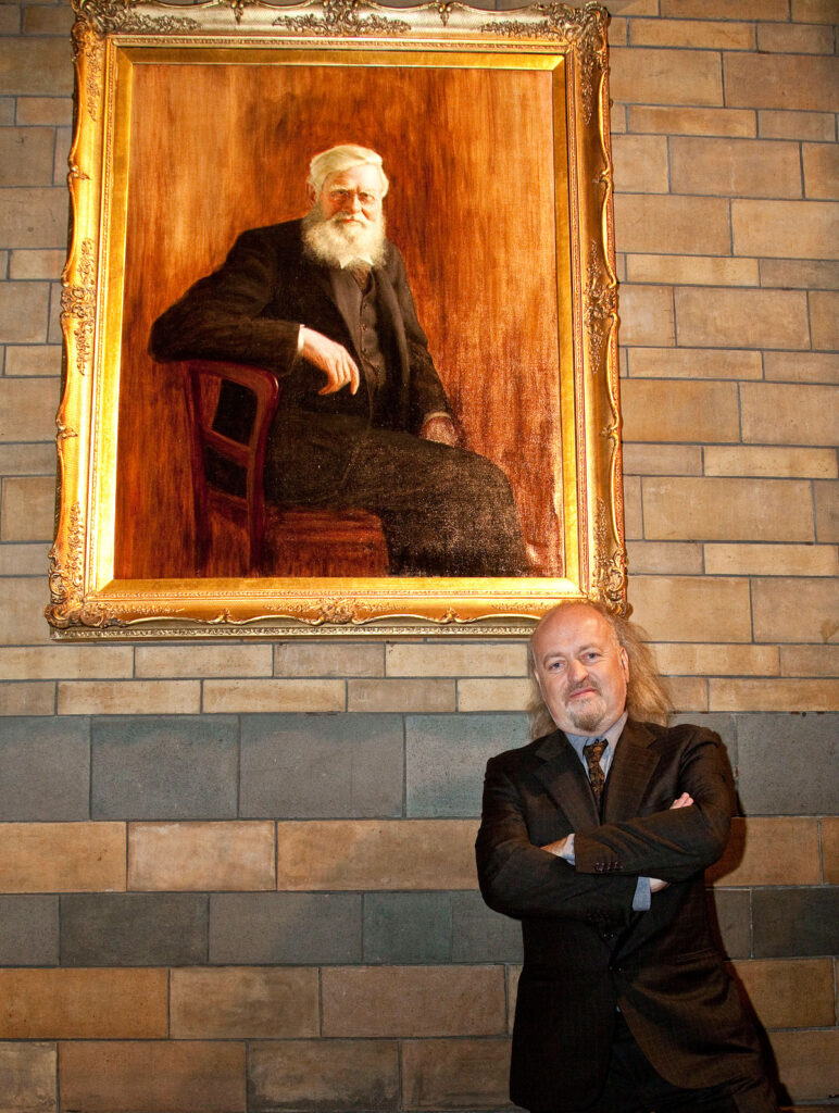 Bill Bailey standing below portrait of Wallace