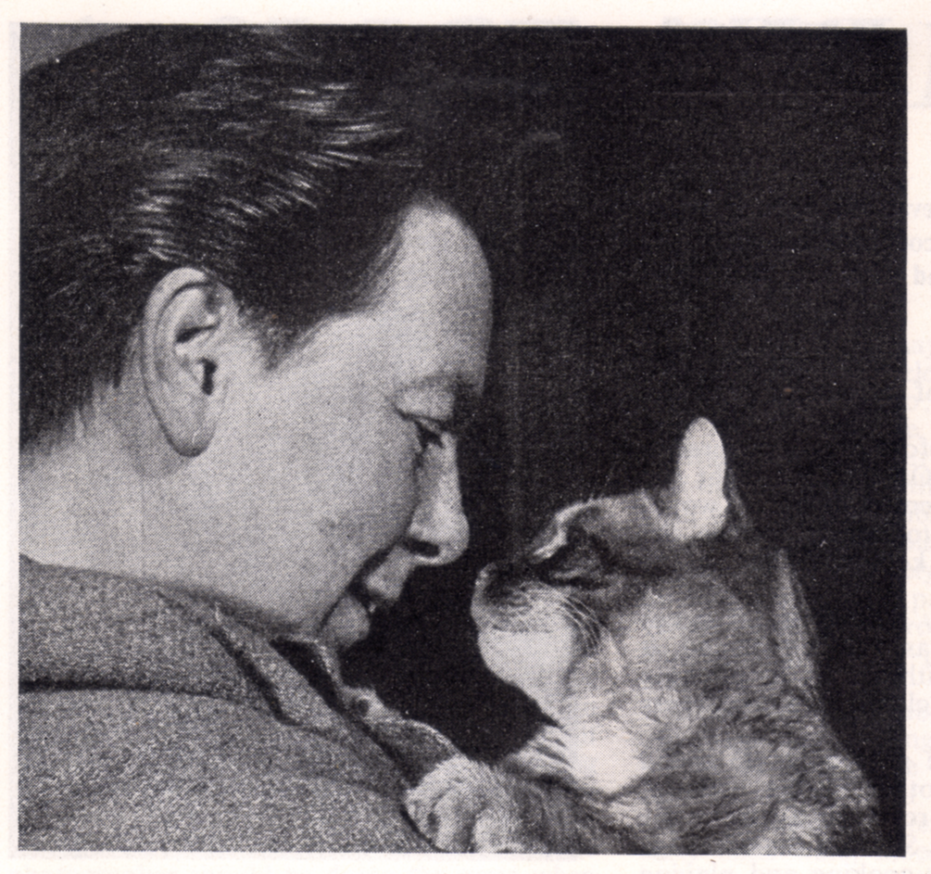 Side photo' of Nick Gray gazing at cat, from Plays and Players Jan 1955.